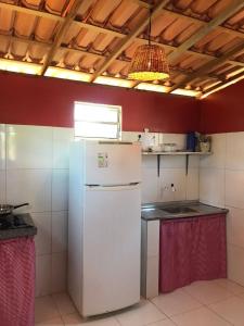 a kitchen with a white refrigerator and a ceiling at Chalé recanto do sol in Santo Amaro