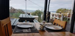 a wooden table with plates and utensils on a balcony at JEJU Doldam B&B in Seogwipo