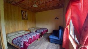 Cabaña “De Aurora” في مازاميتلا: غرفة نوم بسريرين وكرسي ازرق