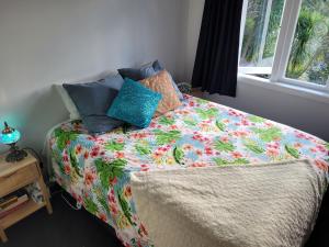 una cama con un edredón colorido y una ventana en City Retreat en Whangarei