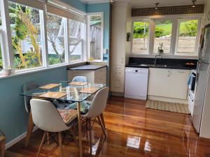 uma cozinha com uma mesa de vidro e armários brancos em City Retreat em Whangarei