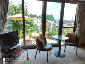 een woonkamer met 2 stoelen, een tafel en een televisie bij Bay View House private room / Vacation STAY 3667 in Otaru