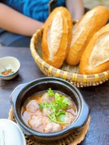 a bowl of soup next to a basket of bread at Maian Natural Farm in Bao Loc