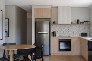 a kitchen with a table and a stainless steel refrigerator at Motel Caloundra in Caloundra