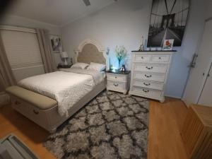 a bedroom with a white bed and a dresser at Little Paris Eiffel Tower Suite in Owings Mills