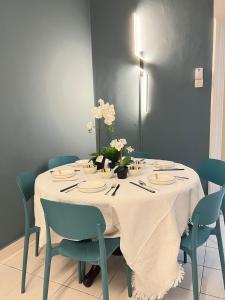 a dining room table with a white tablecloth and blue chairs at SSR 41 SEREMBAN TOWN 4R3B homestay in Seremban
