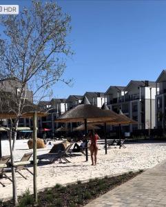 a woman walking on the beach with an umbrella at Munyaka Lagoon Penthouse in Midrand