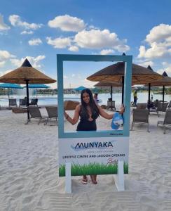 a sign on the beach with a woman standing behind it at Munyaka Lagoon Penthouse in Midrand
