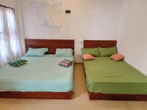 two beds sitting next to each other in a room at Kusuma's Lazy Left in Midigama East