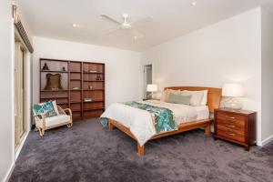 a white bedroom with a bed and a chair at Somerset Sanctuary in Safety Beach in Safety Beach