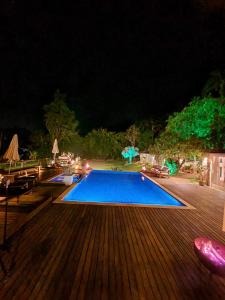 a large swimming pool with a wooden deck at night at Pousada Boutique Itaipava in Itaipava