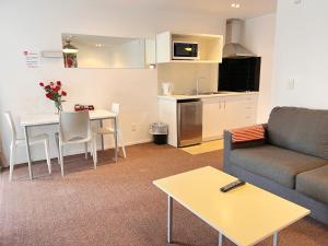 a living room with a couch and a table and a kitchen at Morrinsville Motel in Morrinsville