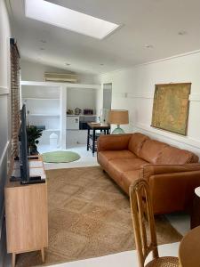 ein Wohnzimmer mit einem braunen Sofa und einem TV in der Unterkunft JMP FLINDERS ACCOMODATION in Flinders