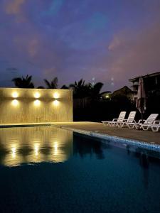 a swimming pool with two lounge chairs next to it at night at Las Hamacas in Canoas de Punta Sal