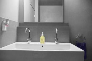 a bathroom sink with two faucets and a soap bottle at Hollywood Guesthouse in Los Angeles +43 photos