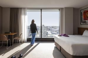 a woman standing in a hotel room looking out the window at Art Series - The Adnate in Perth