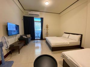 ein Hotelzimmer mit zwei Betten und einem Fernseher in der Unterkunft Taitung Frog Homestay in Taitung