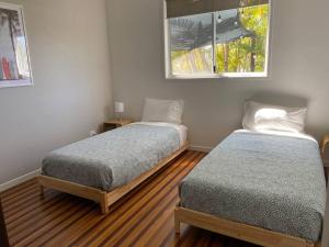 1 dormitorio con 2 camas y ventana en Casa de Palmas Noosa, en Noosaville