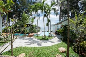 a backyard with a swimming pool and palm trees at BeachHouse Pool Villas Krabi in Krabi