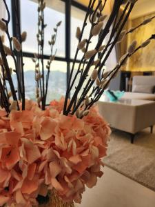 un jarrón lleno de flores rosas en la sala de estar en Urban Suites - Penang, en Jelutong