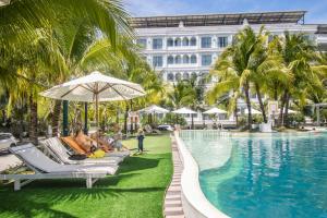 a group of people sitting on lounge chairs next to a swimming pool at Champa Island Nha Trang - Resort Hotel & Spa in Nha Trang