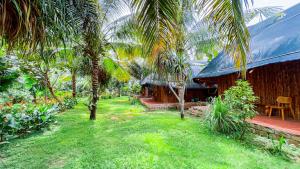 a house with a yard with palm trees in front of it at Me Bungalow Beach Resort in Phan Thiet