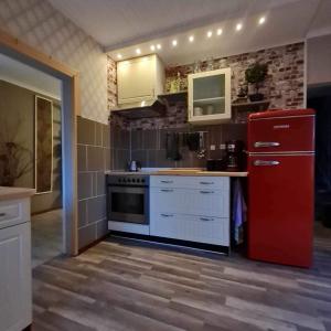 a kitchen with a red refrigerator and white cabinets at Liebevoll renoviertes Ferienhaus im schwedischen Lappland Västerbotten in Björksele