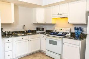 una cocina con armarios blancos y un horno de fogón blanco en King beds, sports teams, work crews, en Sarasota