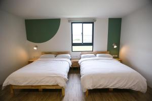 a row of beds in a room with a window at 青逸居 桃園中壢民宿 親子包棟 Qing Yi Ju in Zhongli