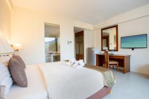 a bedroom with a white bed with a desk and a television at Orchid Garden Hotel in Patong Beach