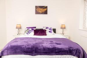 Un dormitorio con una manta morada en una cama en Spacious House near Kings Cross, en Londres