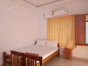 um pequeno quarto com uma cama e uma janela em Somatheertham Panchakarma Resort em Kovalam