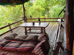 una terraza de madera con mesa y almohadas. en Littleduck bungalow Koh Chang Ranong, en Koh Chang