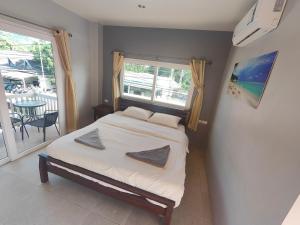 a bedroom with a bed and a window and a table at Moon Travel Phangan in Ban Nua