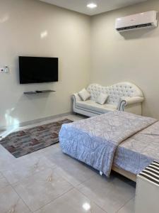 a bedroom with a bed and a couch and a flat screen tv at استراحة الساحل in Dumistān