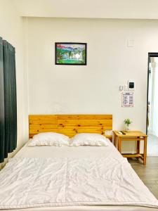 a bedroom with a white bed with a wooden headboard at Homestay KV in Can Tho