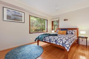 a bedroom with a bed and a window at Arrawong in Merimbula
