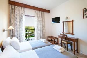 a bedroom with two beds and a desk and a window at Vontzos Hotel in Achladies