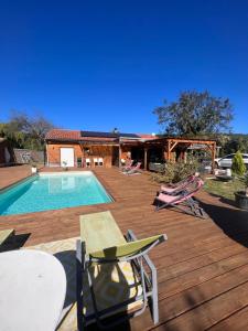 una terraza con piscina y sillas y una casa en Maison en bois , plein pieds,piscine privative en Lavelanet
