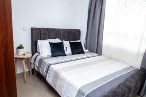 ein Bett mit schwarzweißer Bettwäsche und einem Fenster in der Unterkunft Pridelands Homes in Nairobi