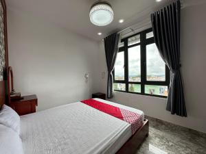 een slaapkamer met een bed en een groot raam bij OYO 1204 Hoang Linh Hotel in Da Lat