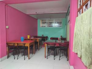 a dining room with tables and chairs and pink walls at Hotel Tawang Holiday in Tawang