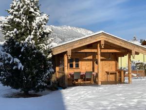 a wooden cabin with a table and chairs in the snow at Chalet Bergliebe in Bad Hofgastein