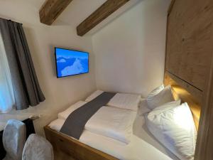 a small bedroom with a bed with a tv on the wall at Chalet Bergliebe in Bad Hofgastein