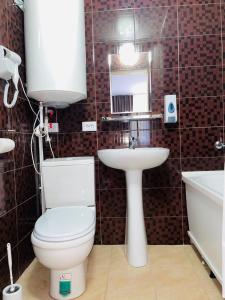La salle de bains est pourvue de toilettes, d'un lavabo et d'une baignoire. dans l'établissement Hotel Palladium, à Chtchoutchinsk
