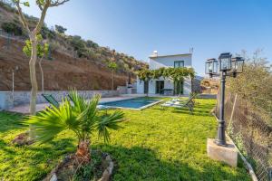 a house with a yard with a palm tree and a lamp at Paredones III Casa Rural Caminito del Rey in Alora