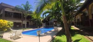 a swimming pool in front of a house with a palm tree at Résidence Kambana in Nosy Be