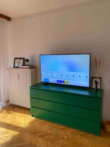 TV de pantalla plana en la parte superior de una cómoda verde en Entire Apartment in the City, en Dunaújváros