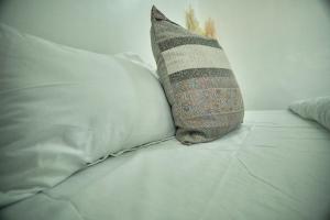 una almohada sentada en una cama junto a algunas almohadas en Lomes cozy home, en Dar es Salaam