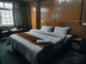 a bedroom with a large bed with wooden walls at Hotel Tawang Holiday in Tawang